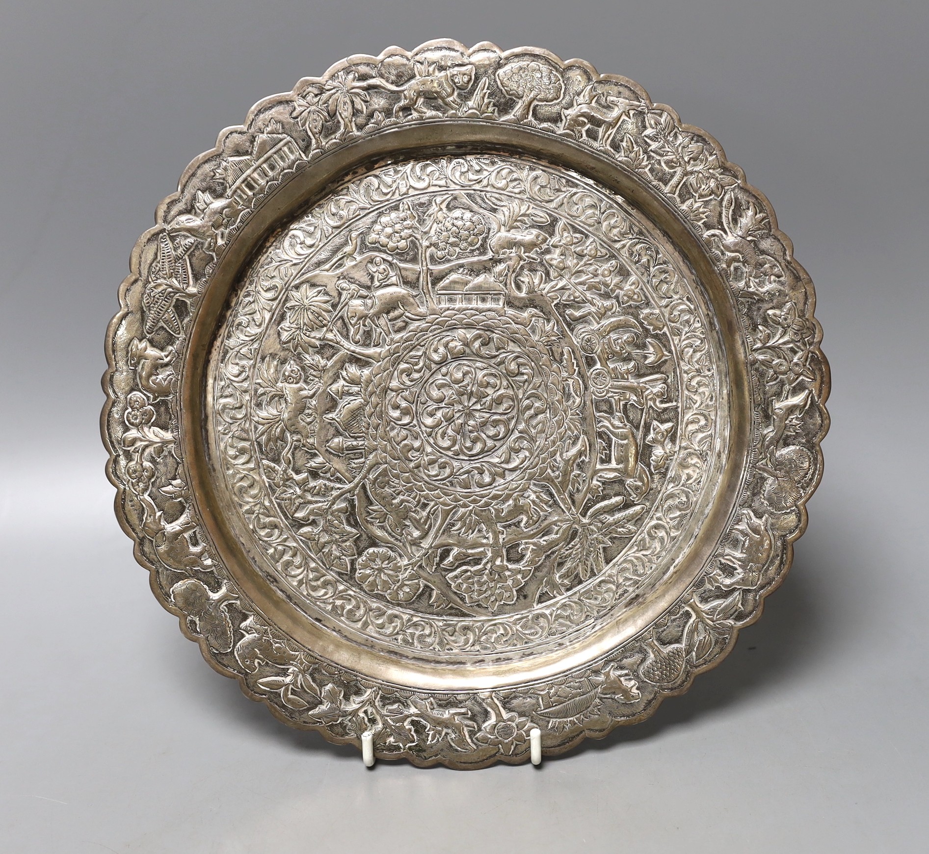 A Indian embossed white metal shallow dish, decorated with animals and foliage amid scrolls, 25.3cm, 348 grams.